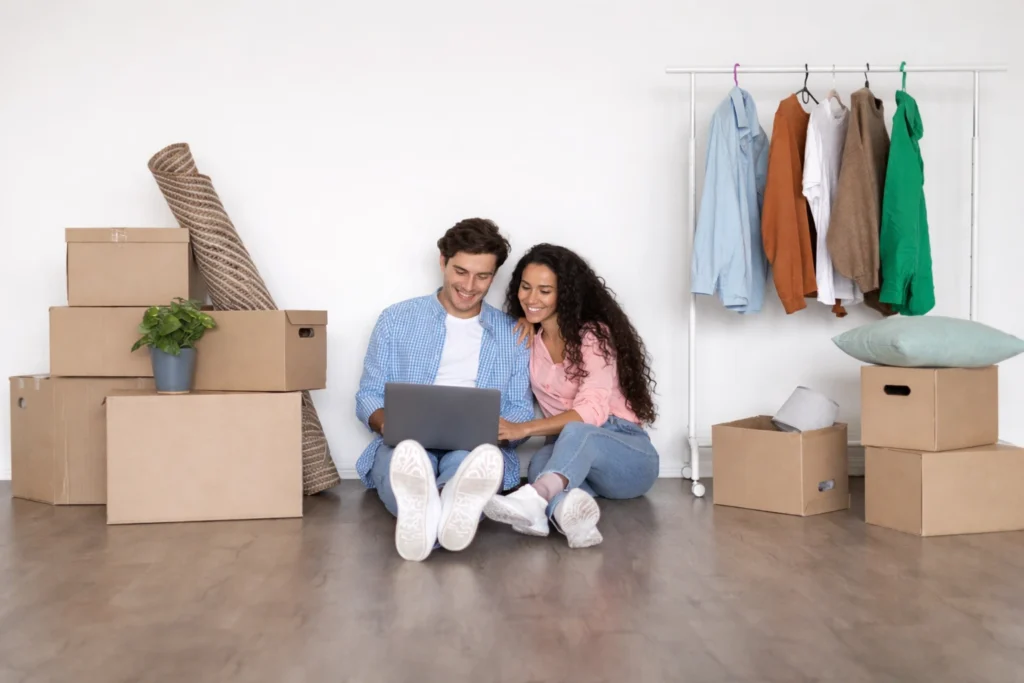 Paar sitzt zwischen Umzugskartons in neuer Wohnung und plant Umzug